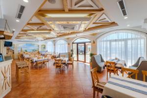 a dining room with tables and chairs and windows at Na Chernomorskoy Hotel in Feodosia