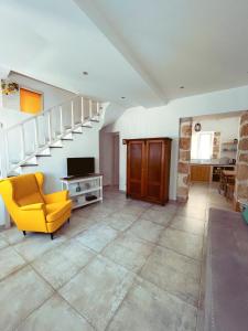 a living room with a yellow chair and a staircase at MaVi House Old Town in Malia
