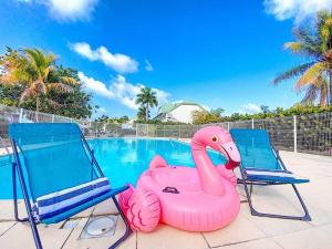 a pink inflatable flamingo next to two chairs and a swimming pool at Maracuja 6, Orient Bay village, walkable beach at 100m in Orient Bay