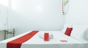 un letto bianco con due cuscini rossi sopra di RedDoorz @ Shukran Rentals OPC Pampanga a Candaba