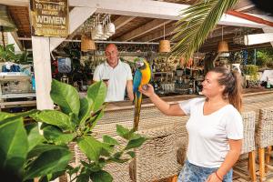 Eine Frau hält einen Papagei in einem Laden. in der Unterkunft Villa Rava Hotel & restaurant in Rava