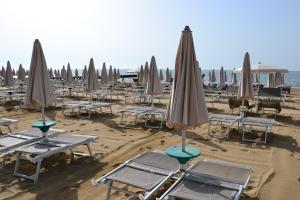 ein paar Stühle und Sonnenschirme am Strand in der Unterkunft Hotel Stockholm in Lido di Jesolo