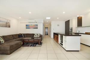 a living room with a couch and a kitchen at Spacious 3 bedroom apartment opposite surf club in Kingscliff