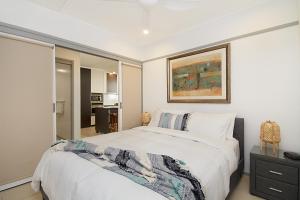 a bedroom with a white bed with a picture on the wall at Spacious 3 bedroom apartment opposite surf club in Kingscliff