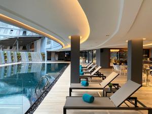 a hotel pool with lounge chairs and a swimming pool at The Oceanic Sportel Phuket - SHA Extra Plus in Phuket