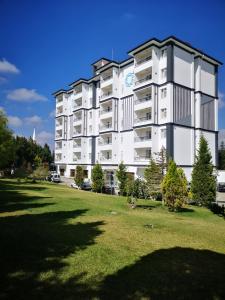 ein großes weißes Apartmenthaus mit einem Grasfeld in der Unterkunft Basaranlar Thermal Otel in Gazligol