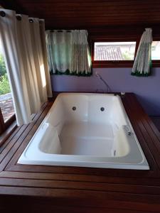a large white bath tub in a room with windows at Caiowa Floripa guesthouse in Florianópolis