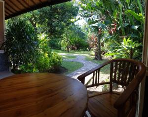 un tavolo e sedie in legno su una veranda con giardino di Mango Tree Inn a Pemuteran