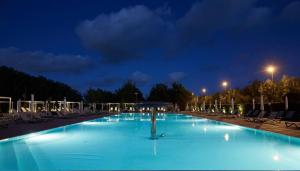 a large swimming pool with chairs and lights at night at Hotel Quadrifoglio in Pontecagnano