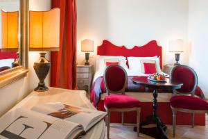 a bedroom with a bed and a table with a book at Castello di Velona Resort, Thermal SPA & Winery in Montalcino