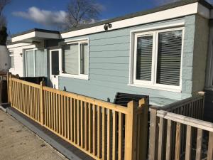 a small blue house with a wooden fence at 2 Bedroom Chalet SB11, Sandown Bay, Dog Friendly in Sandown