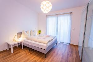 een witte slaapkamer met een bed en een kroonluchter bij City Dream 1 by Alpenidyll Apartments in Schladming