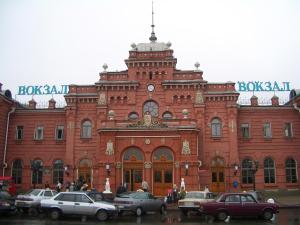 un gran edificio de ladrillo rojo con coches aparcados delante en Mini-Hotel na Naberezhnoy, en Kazán