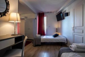a room with two beds and a desk and a mirror at Hôtel Le Mistral in Marseille