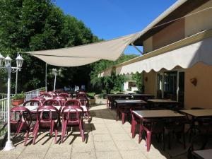 un groupe de tables et de chaises avec un parasol blanc dans l'établissement Le Pidanoux, à Saint-Julien-du-Verdon