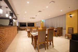 una sala da pranzo con tavoli e sedie in legno di Hotel Palm International a Butwāl