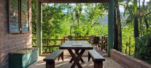a wooden table on a porch with a view of trees at Bangalô do Rio - Timbé do Sul in Timbe do Sul