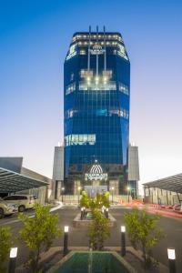 a tall blue glass building in a parking lot at Tulip Plaza Hotel in Sakakah