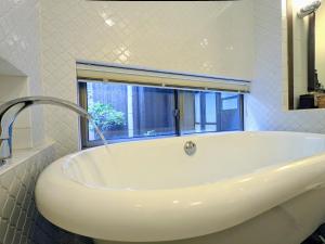 uma banheira branca na casa de banho com uma janela em KyoMachiya Stars em Quioto