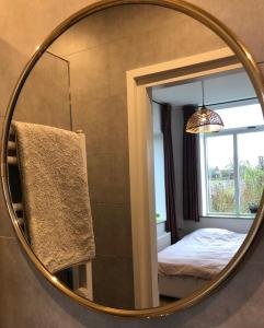 einen Spiegel in einem Zimmer mit einem Bett und einem Fenster in der Unterkunft Huisje op Bioboerderij, kust, polder en rust in Hoofdplaat