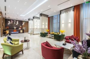 een lobby met groene en rode stoelen en tafels bij Tulip Plaza Hotel in Sakakah