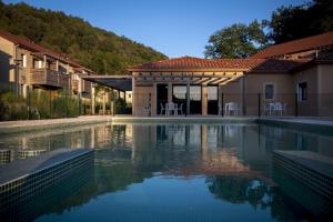 a swimming pool in front of a house at Vacancéole - Résidence Le Clos du Rocher in Les Eyzies-de-Tayac