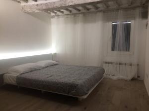 een witte slaapkamer met een bed en een raam bij Pispini Apartment in Siena