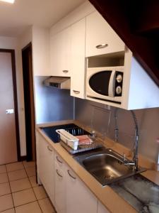 a kitchen with a sink and a microwave at Duplex Climatisé - Piscine-Plage - 1 à 4 personnes in Sainte-Anne