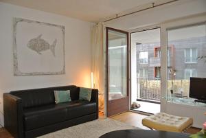 sala de estar con sofá de cuero negro y ventana en Wohnung Tide, en Hörnum