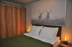 sypialnia z łóżkiem z dwoma obrazami jelenia na ścianie w obiekcie Hashtag Studio Borovets w Borowcu