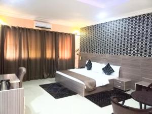 a bedroom with a bed and a table in a room at Fawzy Hotel in Ibadan