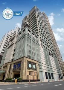 ein hohes Gebäude mit einer Uhr davor in der Unterkunft The Duchess Hotel in Bangkok