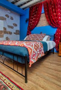a bedroom with blue walls and a bed with red curtains at Fatma Hanoum boutique hotel in Rhodes Town