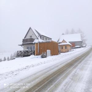 a snow covered street with houses and a road at Domek pod chałpom sauna & bania in Gliczarów +13 photos