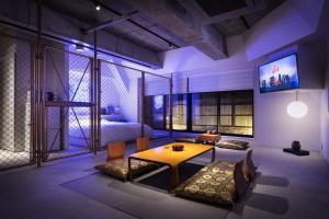 a room with a table, chairs and a television at Artist Hotel - BnA STUDIO Akihabara in Tokyo