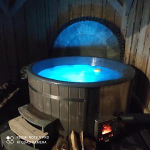 a hot tub with a blue water in it at Domek pod chałpom sauna & bania in Gliczarów