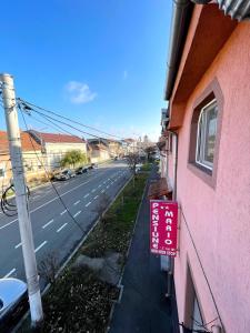 un cartello sul lato di un edificio rosa vicino a una strada di Pensiunea Mario a Arad