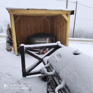 a snow covered grill in front of a shed at Domek pod chałpom sauna & bania in Gliczarów