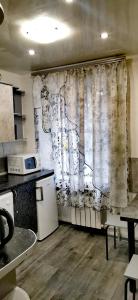 a kitchen with a curtain and a table and a refrigerator at Квартира на проспекте Поля 127 in Dnipro