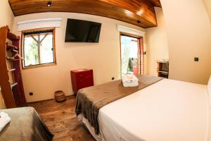 a bedroom with a large bed and a flat screen tv at Bossa Beach House in Ilha do Mel