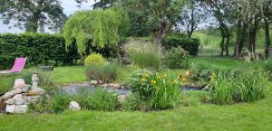 un jardin avec un étang et des fleurs dans l'herbe dans l'établissement La Magnanerie, à Savigny-en-véron