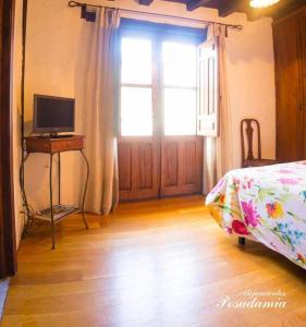 a bedroom with a bed and a desk with a television at Posada El Canchal in Arenas de San Pedro