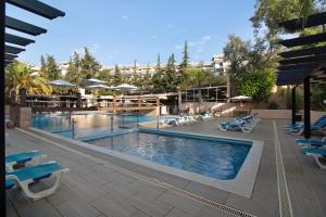 una piscina en un hotel con sillas y sombrillas en T2 Balaia, en Albufeira