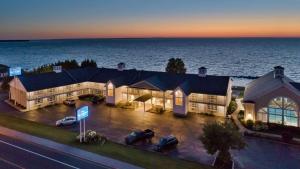 an aerial view of a hotel with the ocean behind it at Baymont by Wyndham St. Ignace Lakefront in Saint Ignace