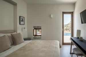 een slaapkamer met een bed, een bureau en een raam bij Monolithoi Villas in Piyí