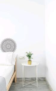 una mesa blanca con una planta junto a una cama en Casa de la Alameda, en Sevilla