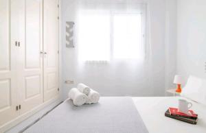 een witte slaapkamer met handdoeken op een bed bij Casa de la Alameda in Sevilla