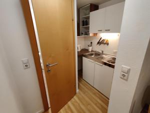 eine kleine Küche mit weißen Schränken und einer Tür in der Unterkunft Appartements Berger Kitzbühel in Kitzbühel