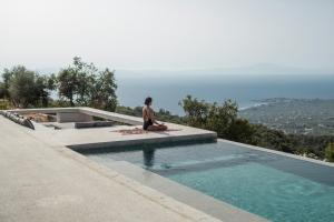 una mujer sentada en el borde de una piscina en Monolithoi Villas, en Piyí