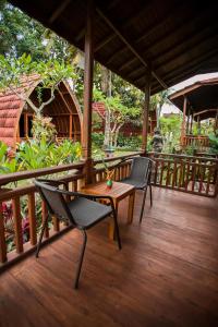 una terrazza in legno con 2 sedie e un tavolo di The Dukuh Retreat a Tabanan